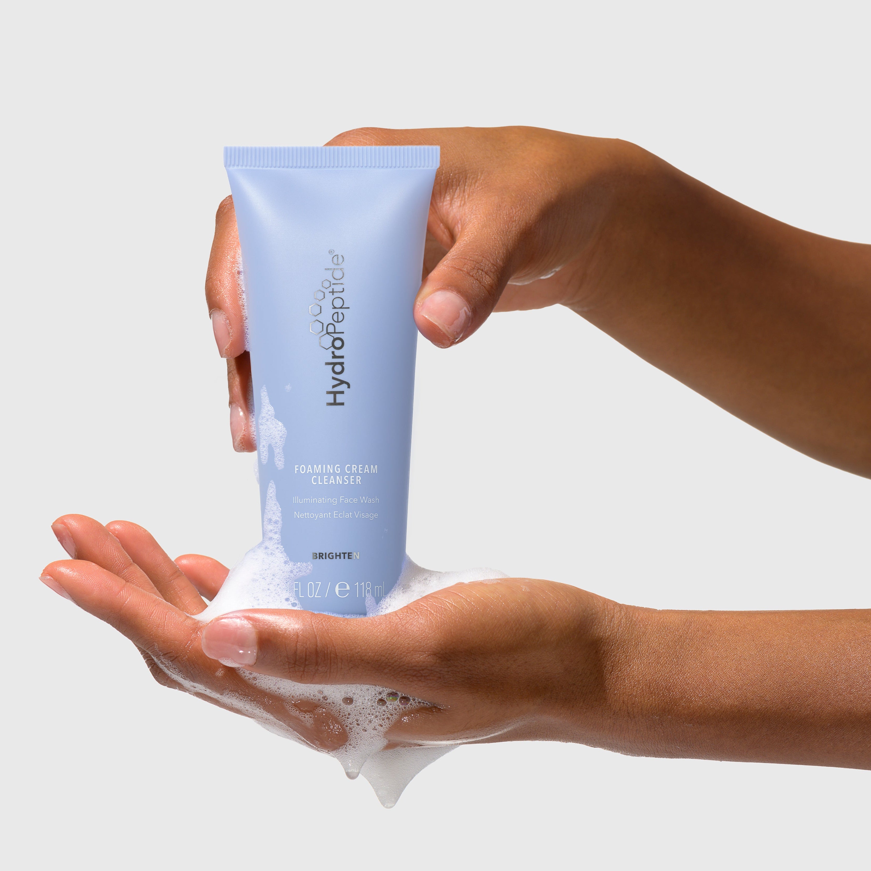 Person holding a tube of Hydro Boost cream with visible foam on a plain background