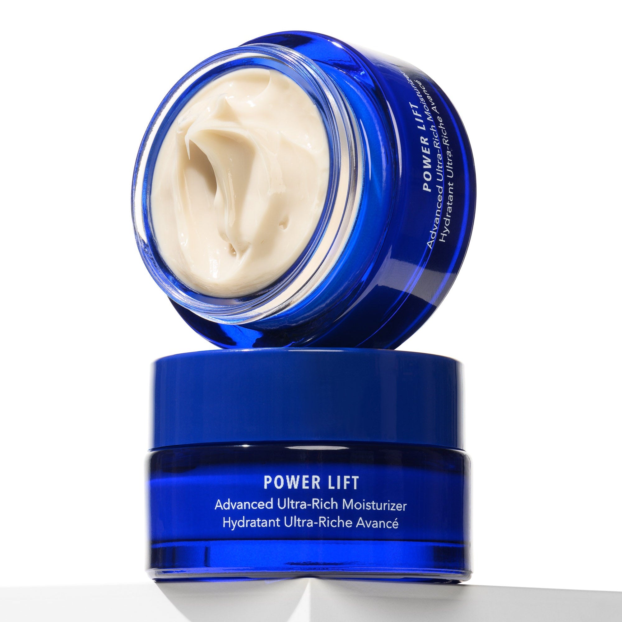 Blue skincare jar with white cream on a white background